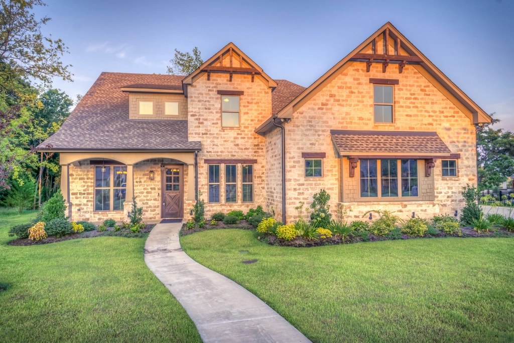 Brick house with steep tiled roofs, dormer and gables above a front lawn