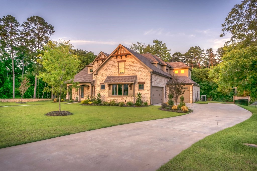 Detached house with tiled roofs set among trees at the end of a curved drive