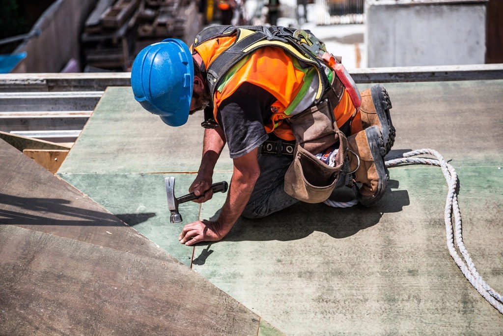Roofer in a hard hat fixing down a felt flat roof