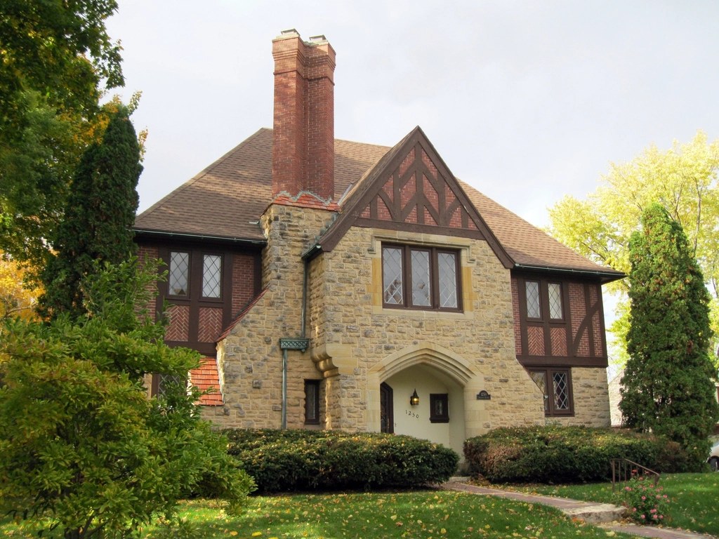 Stone and timber-framed house with a tall brick chimney and tiled roof